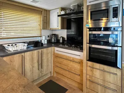 a kitchen with wooden cabinets and stainless steel appliances at Millars Caravan in Ayr