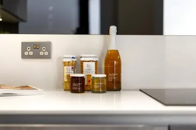 a counter with four jars of honey next to a bottle at Stylish 2-Bedroom Flat On Seven Sisters Rd in Moffat