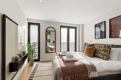 a bedroom with a large bed and a mirror at Bright 3BR London Flat w Full Kitchen in Moffat