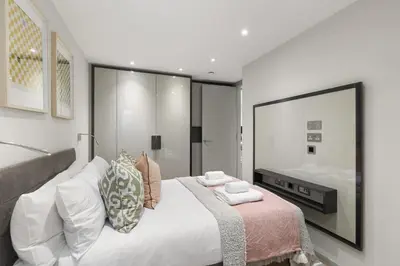 a bedroom with a large white bed and a mirror at Bright 3BR London Flat w Full Kitchen in Moffat