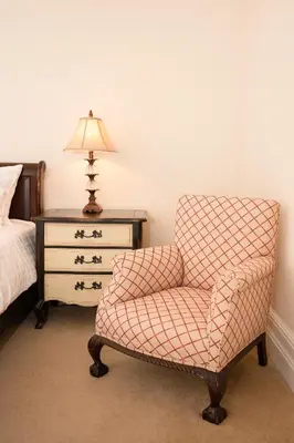 a bedroom with a chair and a bed and a lamp at Springkell in Eaglesfield