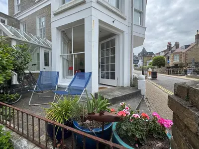a balcony with two blue chairs and flowers at Regents House, ground floor apartment with sea views in Moffat