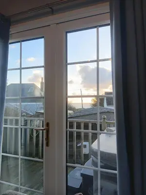 a sliding glass door with a view of a balcony at 'Sunset Lodge' Peaceful Coastal Retreat with Hot Tub in Monreith
