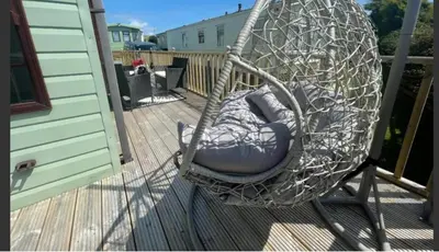 a swing sitting on a deck on a porch at 'Sunset Lodge' Peaceful Coastal Retreat with Hot Tub in Monreith