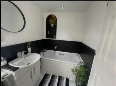 a bathroom with a tub and a sink and a mirror at 'Sunset Lodge' Peaceful Coastal Retreat with Hot Tub in Monreith
