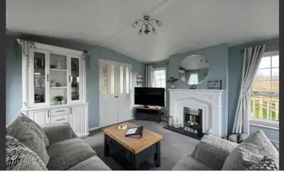 a living room with a couch and a fireplace at 'Sunset Lodge' Peaceful Coastal Retreat with Hot Tub in Monreith