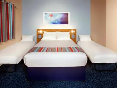two beds in a hotel room with white beds at Travelodge Carlisle Central in Carlisle