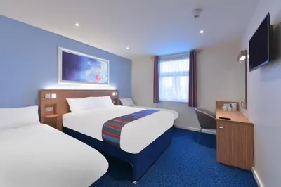 a hotel room with two beds and a desk at Travelodge Carlisle Central in Carlisle