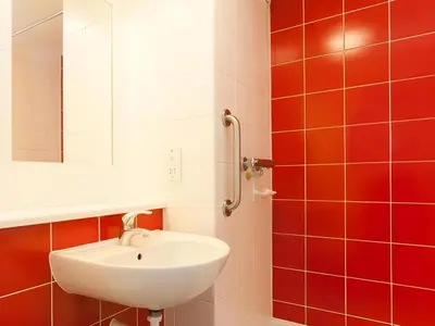 a bathroom with a white sink and red tiles at Travelodge Carlisle Central in Carlisle