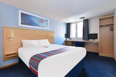 a hotel room with a large bed and a desk at Travelodge Dumfries in Collin