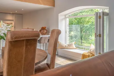 a dining room with a table and a window at Luxurious Barn within easy reach of South Lakes! in Boot