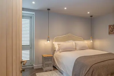 a bedroom with a bed and a nightstand next to a window at Luxurious Barn within easy reach of South Lakes! in Boot