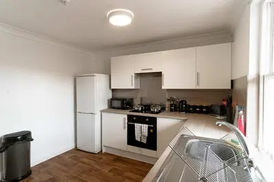a kitchen with white cabinets and a white refrigerator at Bright 1 Bed Harbour-side Apartment in Whitehaven in Whitehaven
