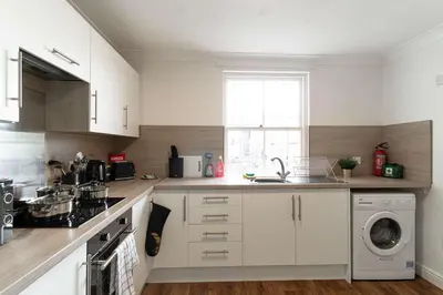 a kitchen with white cabinets and a washing machine at Bright 1 Bed Harbour-side Apartment in Whitehaven in Whitehaven