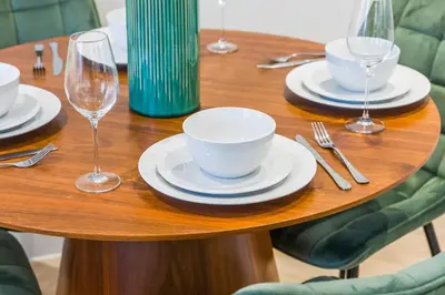 a wooden table with plates and wine glasses on it at Central Jewellery Quarter 1-Bedroom with Parking in Moffat