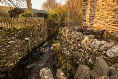 a stone wall with a table and chairs next to it at Stables Cottage - Wythop Mill in Embleton