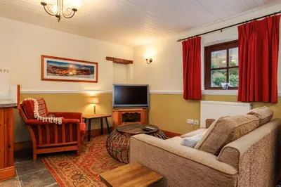 a living room with a couch and a tv at Stables Cottage - Wythop Mill in Embleton