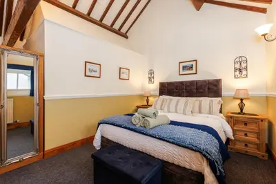 a bedroom with a large bed and a large mirror at Stables Cottage - Wythop Mill in Embleton