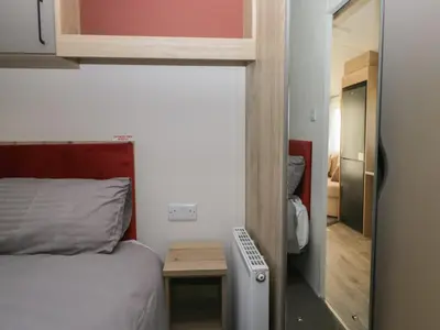 a bedroom with a bed and a small table next to a door at Guillemot in St Bees