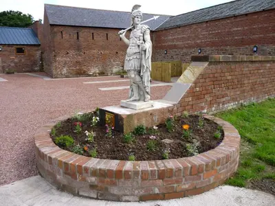 a statue of a woman standing in a garden at Stanegate, Irthington on Hadrians Wall in Irthington