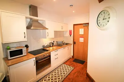 a kitchen with white cabinets and a clock on the wall at Turret, Irthington on Hadrians Wall in Irthington