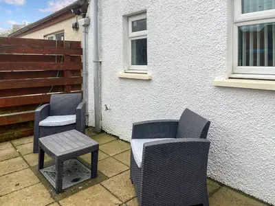 two chairs and a stool sitting on a patio at Taigh-Beag - Uk50660 in Wigtown
