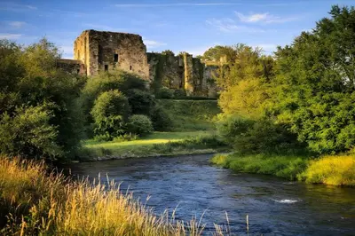 a view of a river with a castle in the background at Riverside Heights- Dog Friendly Lakeland Retreat in Town Centre in Cockermouth