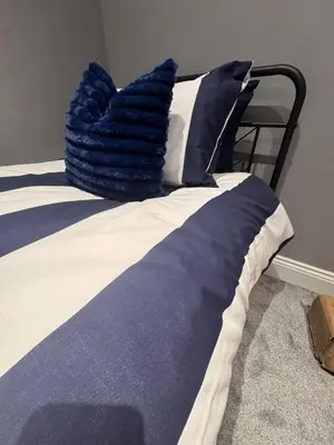 a bed with a blue and white comforter at Granville Road, near Hospital, sleeps 5 in Carlisle