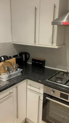 a kitchen with white cabinets and a stove top oven at Peace Haven Hendon London NW4 in Moffat