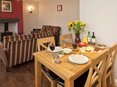 a wooden table with plates and wine glasses and a couch at 22 Rose Terrace in Keswick