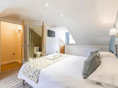 a bedroom with a white bed and a bathroom at Mary's Cottage in Keswick