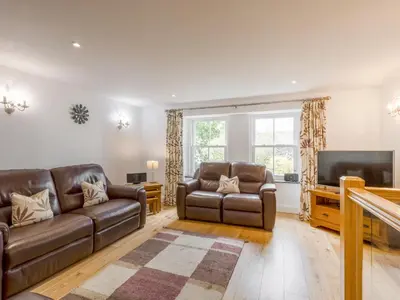 a living room with leather furniture and a flat screen tv at Mary's Cottage in Keswick
