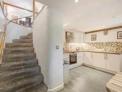 a kitchen and staircase in a home with white walls at Mary's Cottage in Keswick