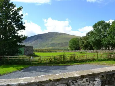 a field with a fence and a mountain in the background at Crofthead in Hesket Newmarket