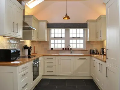 a kitchen with white cabinets and a sink at Crofthead in Hesket Newmarket