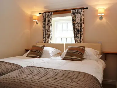 two twin beds in a room with a window at Crofthead in Hesket Newmarket