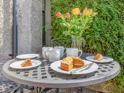 a table with plates of cake and a vase of flowers at Jame's Cottage in Keswick