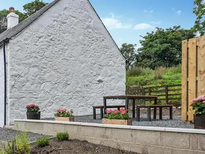 a table and benches in front of a building at Dairy Cottage in Girvan