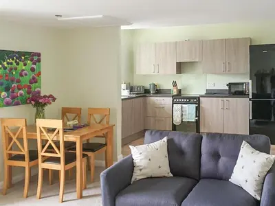 a living room with a couch and a table and a kitchen at Dairy Cottage in Girvan