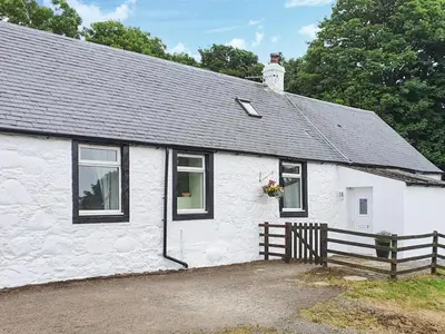 a white cottage with a black roof at Dairy Cottage in Girvan
