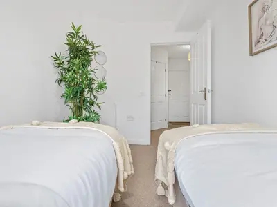 two beds in a white room with a plant at Modern 2-Bedroom Apartment with Free Parking in Warrington in Moffat