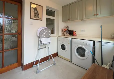 a laundry room with a washing machine and a chair at Wreay Lodge - Fellside Home with Lake Views in Watermillock