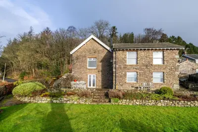 a brick house with a stone wall at Wreay Lodge - Fellside Home with Lake Views in Watermillock