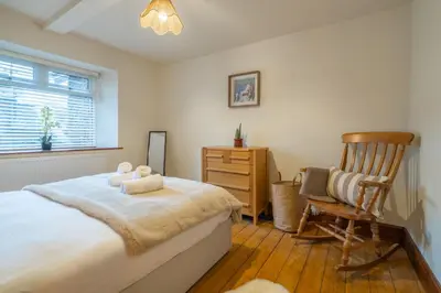 a bedroom with a bed and a wooden chair at Wreay Lodge - Fellside Home with Lake Views in Watermillock