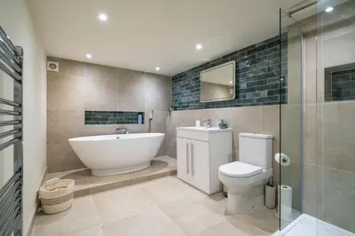 a bathroom with a tub and a toilet and a sink at Wreay Lodge - Fellside Home with Lake Views in Watermillock
