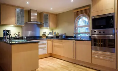 a kitchen with stainless steel appliances and wooden cabinets at Underscar - Scafell in Applethwaite