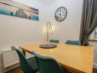 a dining room table with chairs and a clock on the wall at 6 Hallin Fell in Watermillock