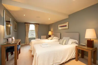 a bedroom with two beds and a desk and a window at Castlerigg in Applethwaite