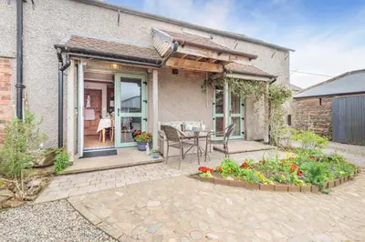 a house with a patio with a table and some flowers at 3 Bed in Kirkbampton oc-l32005 in Burgh by Sands