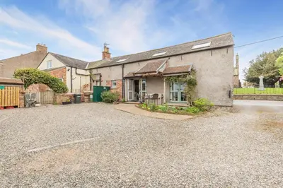 an old house with a gravel driveway in front of it at 3 Bed in Kirkbampton oc-l32005 in Burgh by Sands